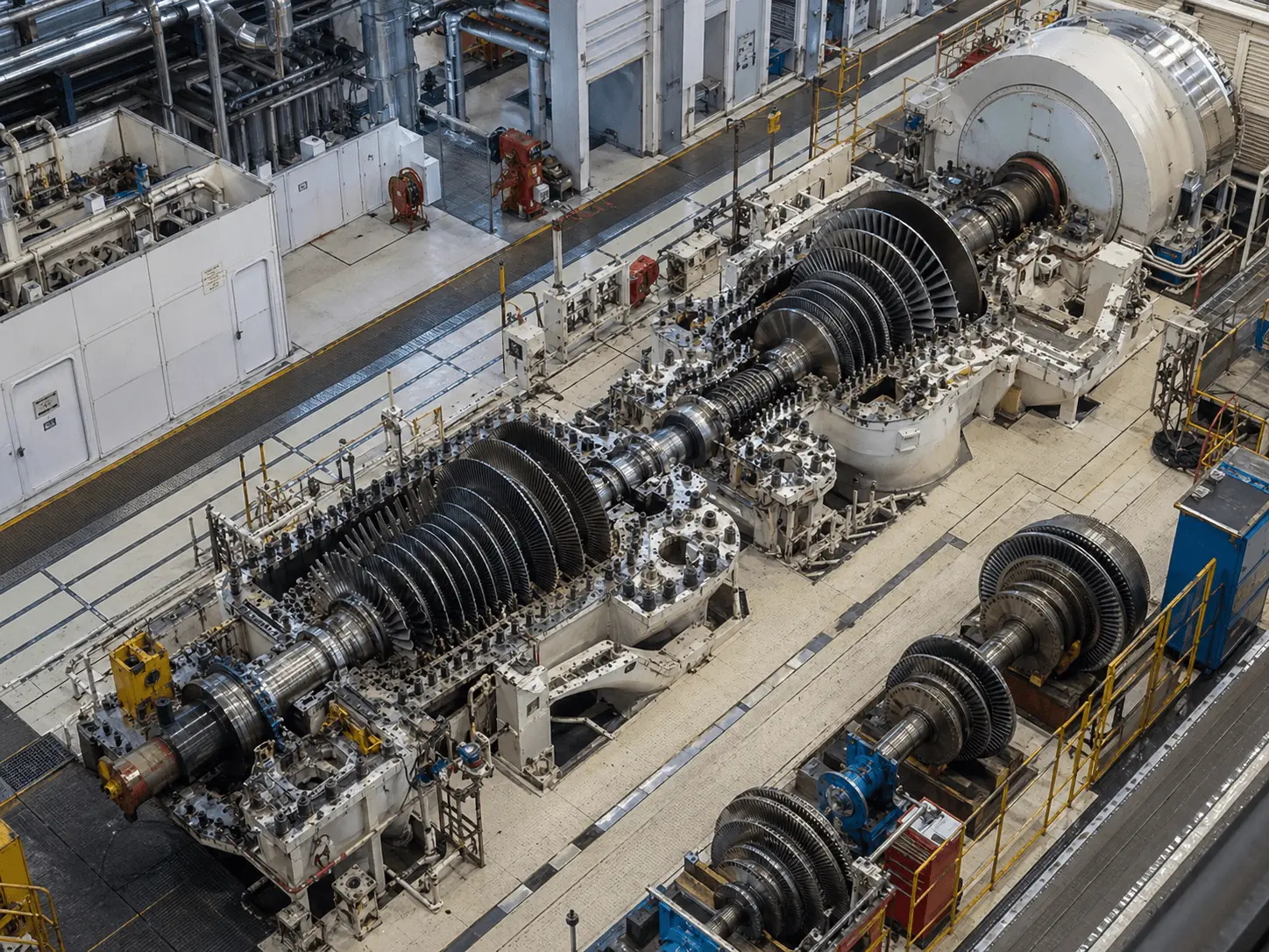 Overhead view of industrial gas turbine rotor assemblies undergoing repair and maintenance in a power plant service bay