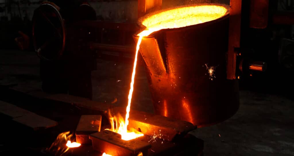 Molten metal pouring from a crucible into a foundry mold